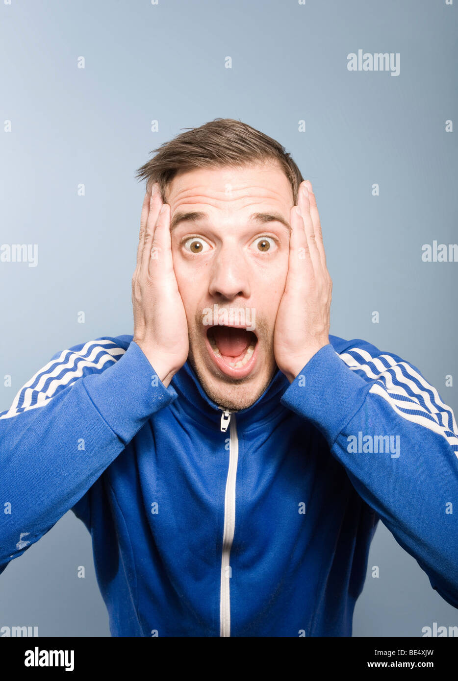 Young man screaming while posing in a retro style Adidas sport suit Stock Photo