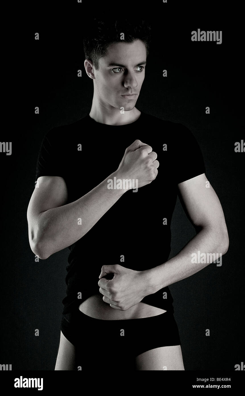 Young man, black clothes, arms tense, looking to the side Stock Photo