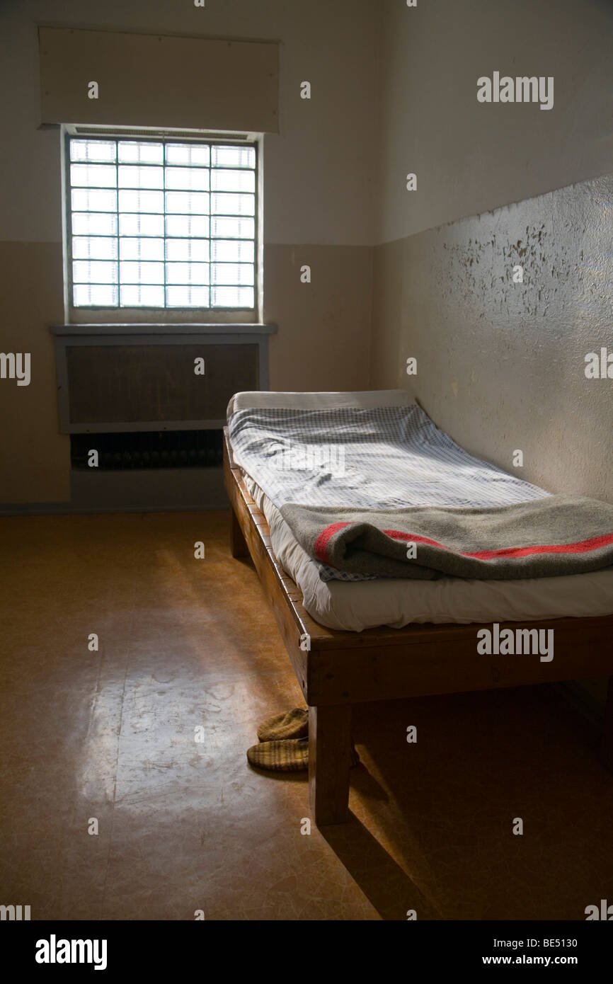 Cot with original bed covers, blanket and slippers in a cell, Berlin