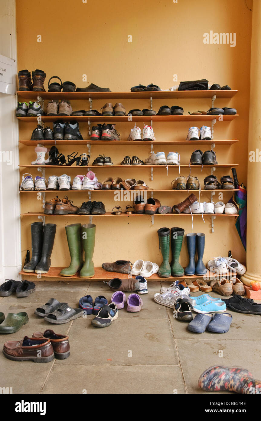 Many shoes on shelf/shelves and on the ground in an outdoor porch area. Stock Photo