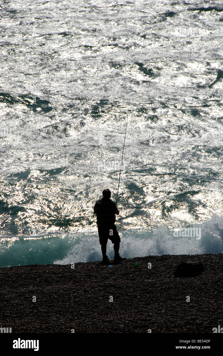 Fisherman sea fishing Chesil Beach or Chesil Bank a shingle barrier beach part of Jurassic Coast