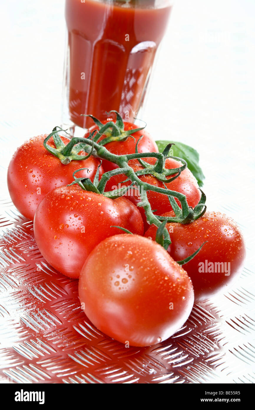 Beefsteak tomatoes on chequer plate in front of tomato juice Stock Photo