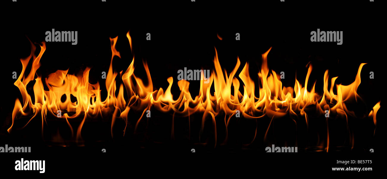 Tongues of fire in a panoramic view over a black background. Stock Photo