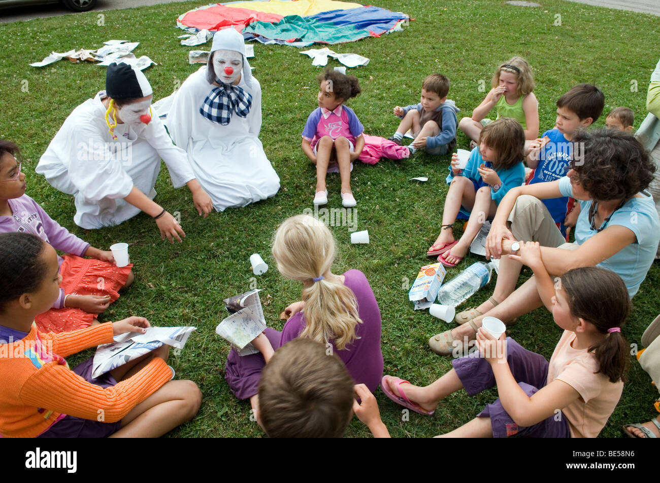two clowns meeting a group of children during a summer camp Stock Photo