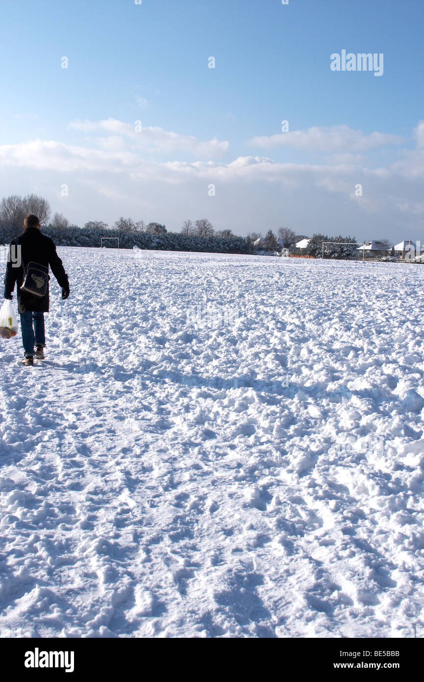 Man walking across a park covered in snow Stock Photo - Alamy