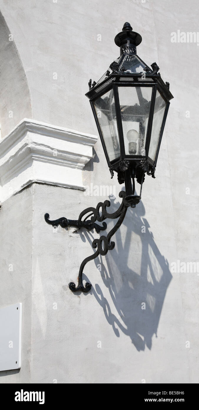 Old wrought iron lamp on a gray, plastered wall at a doorway. Stock Photo