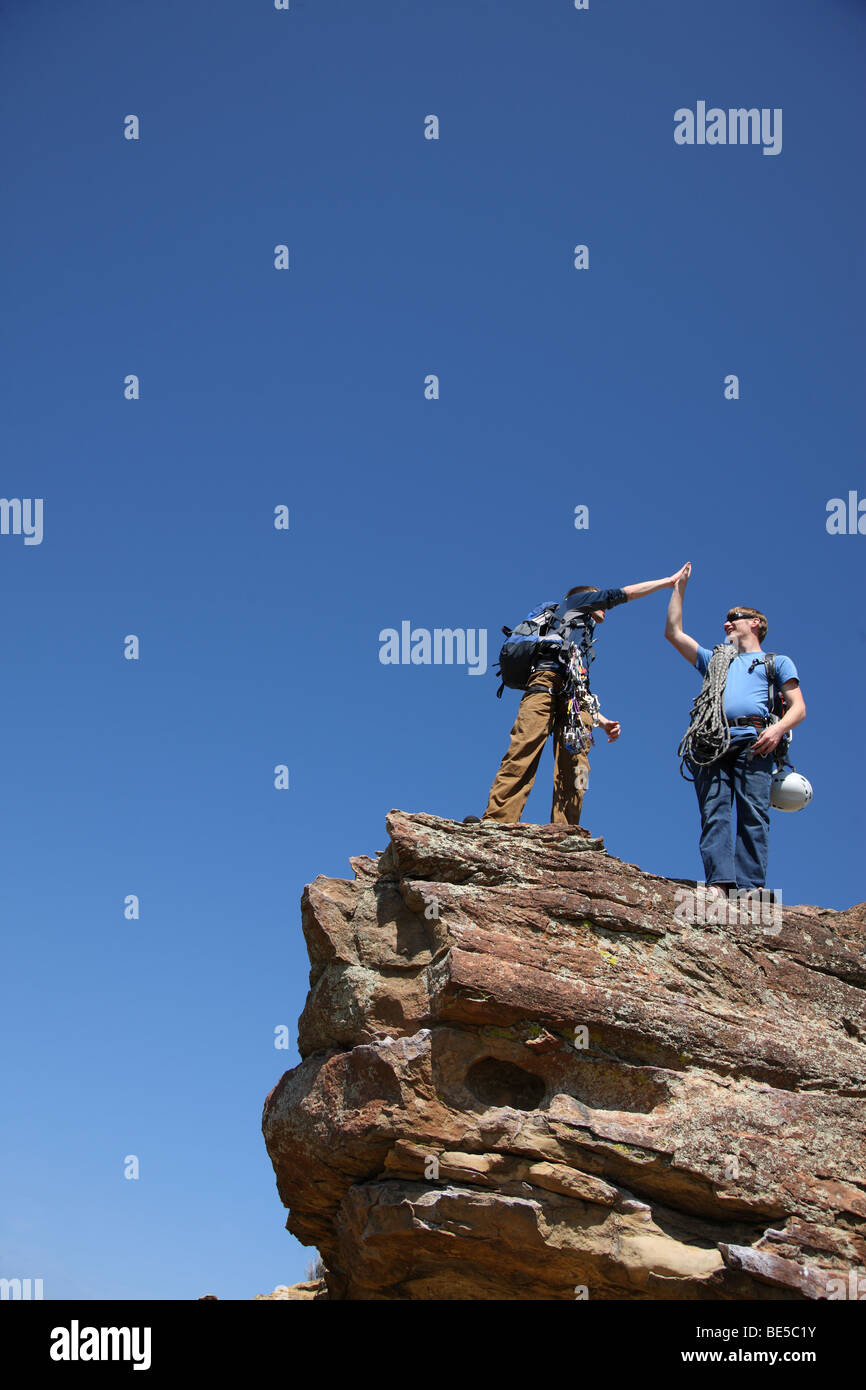 Rock climbers congratulate each other at top of rock Stock Photo