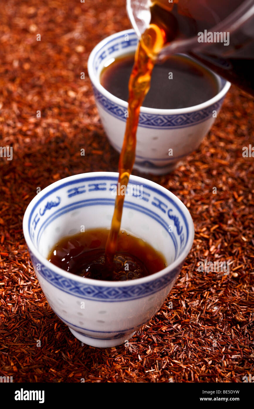 Black tea being poured into Asian teacups Stock Photo