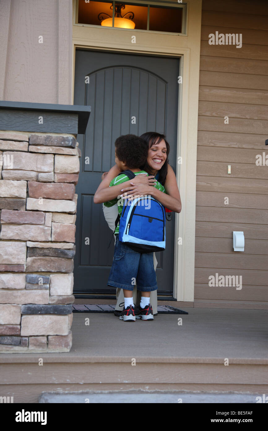 Mother gives young son a hug on front porch Stock Photo