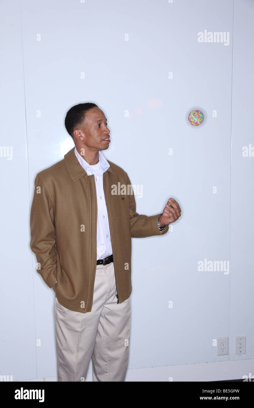 Man tossing rubber band ball in air Stock Photo