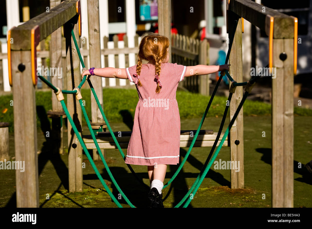 small redhead girl balancing on a tightrope at playtime Stock Photo