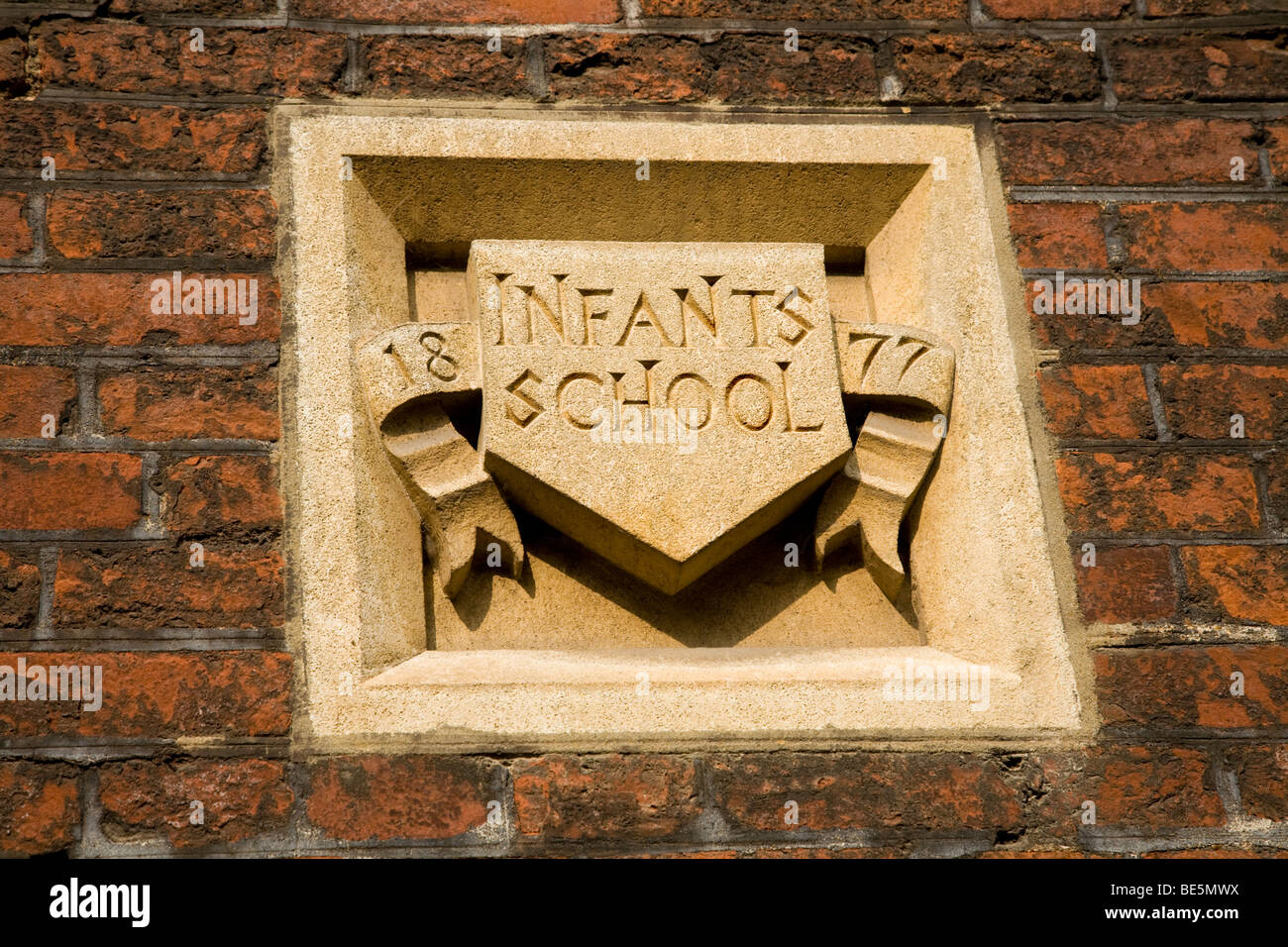Carved stone plaque – dated 1877 –  above the entrance to the Infants' School in Tennis Court Lane at Hampton Court Palace UK. Stock Photo