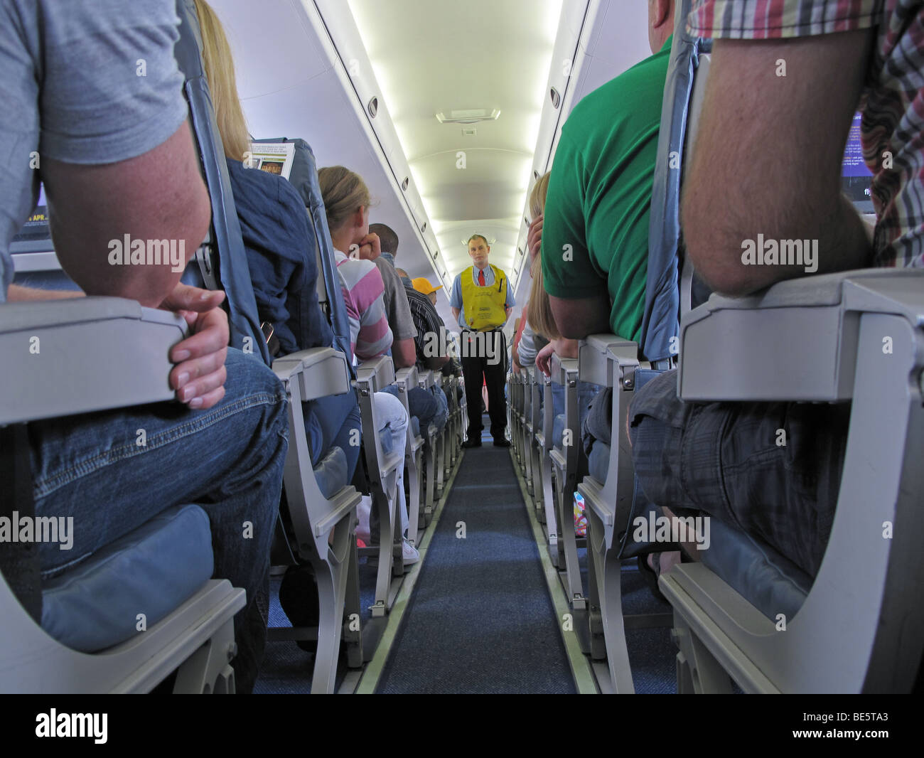 A flight attendant or steward gives safety instructions during a Flybe flight from Guernsey to London Gatwick Stock Photo