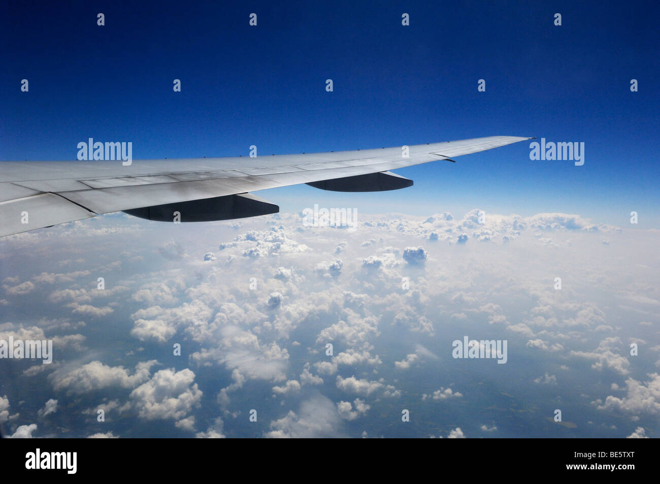 Plane wing above white cumulus clouds Stock Photo