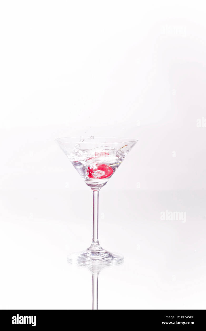Cocktail cherry falling into a Martini glass Stock Photo