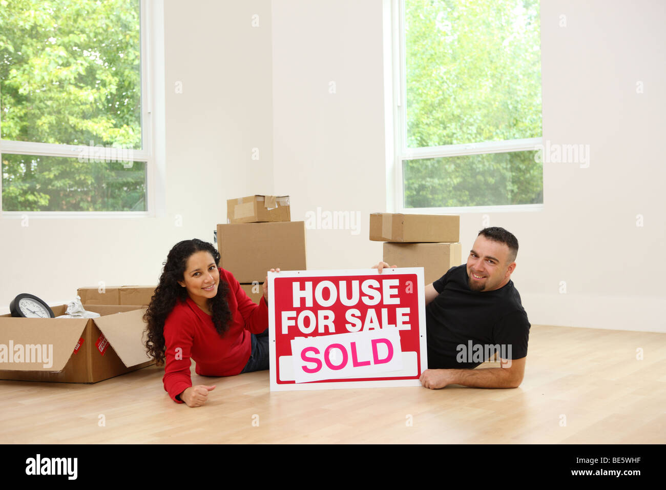 Couple in new home with real estate sign Stock Photo