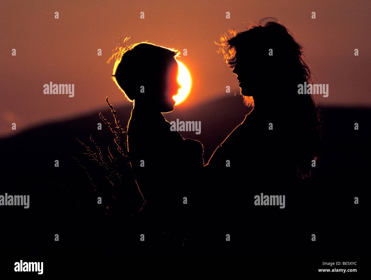 Silhouette Of Mother And Son Talking With Sun And Sunset In Stock