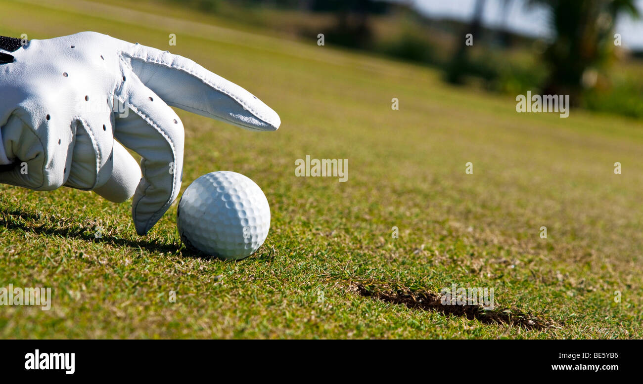 Putting without golf clubs, hand is tipping a golf ball into the hole Stock Photo