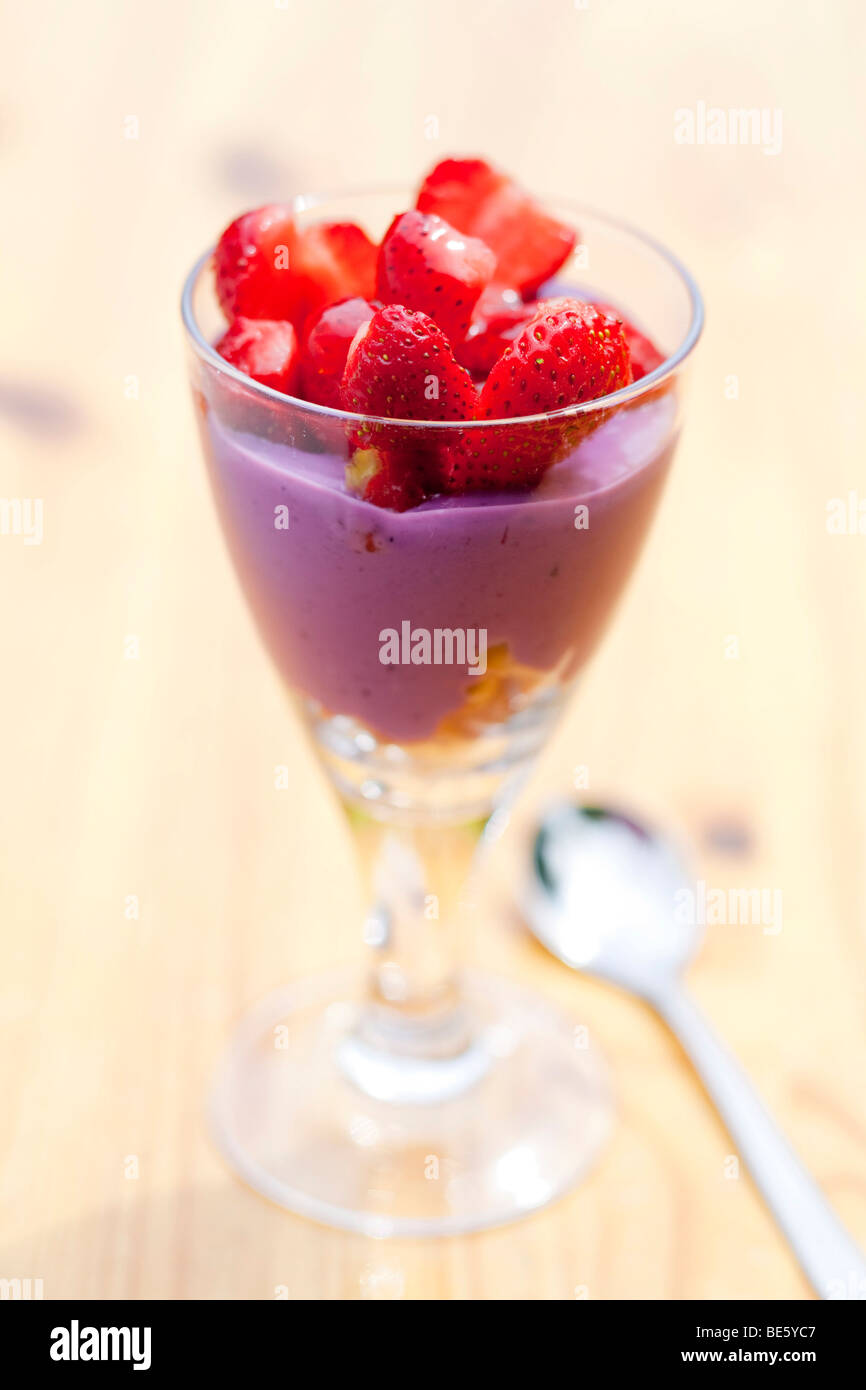 Blueberry yoghurt on cornflakes, topped with honey-covered strawberries Stock Photo