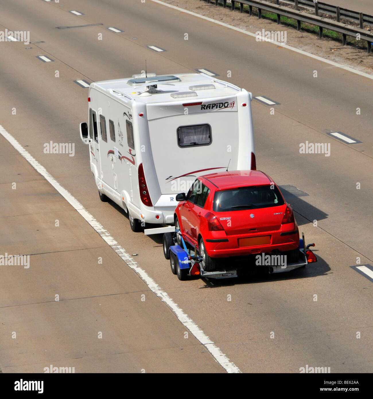 M25 motorway camper van obscured numberplate towing a Suzuki Swift car  Stock Photo - Alamy