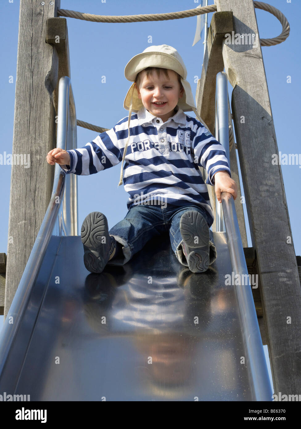 Young boy, 2 years old, sitting on a slide Stock Photo