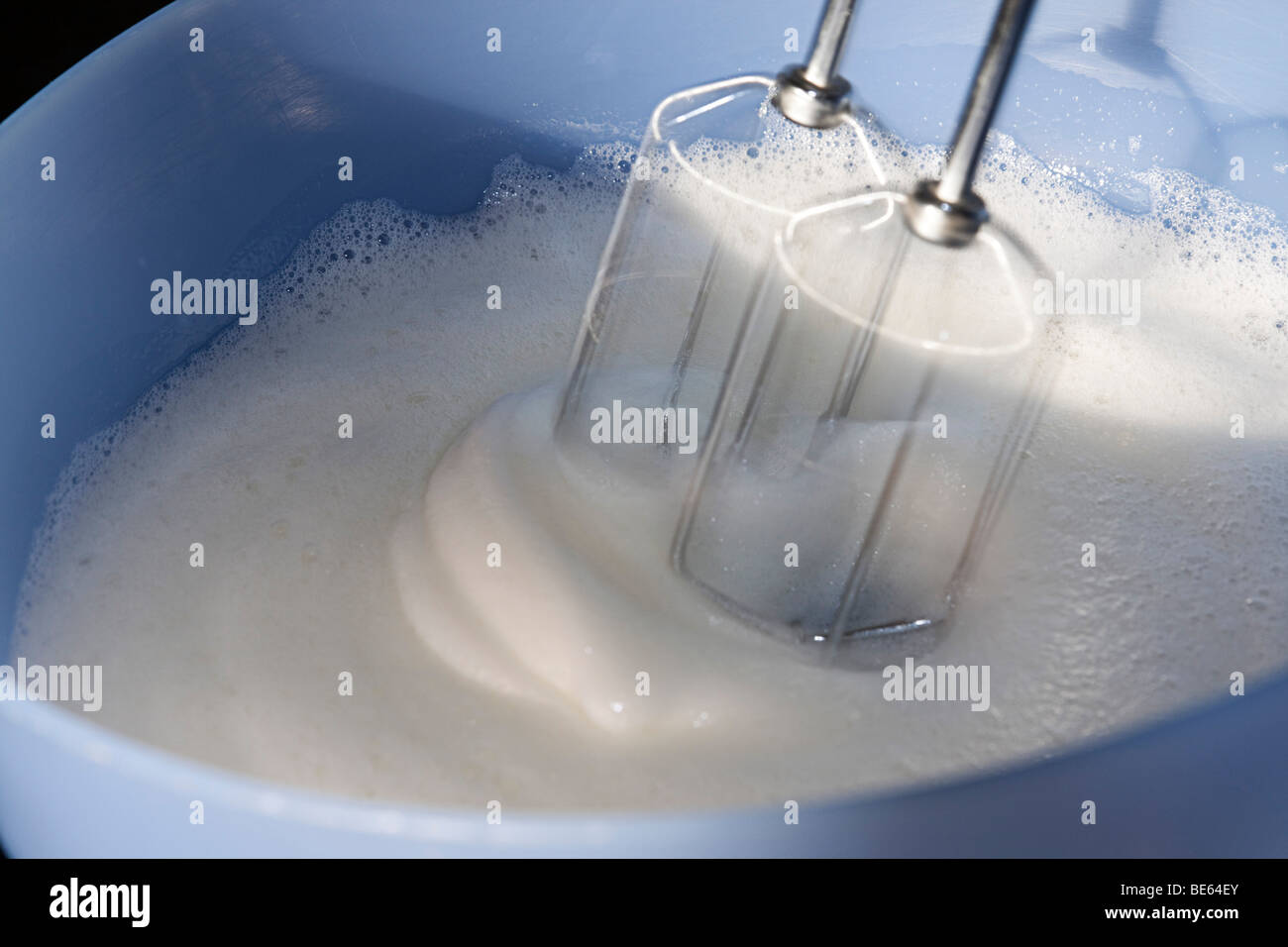 Beating egg whites in a mixing bowl with electric mixer. Stock Photo