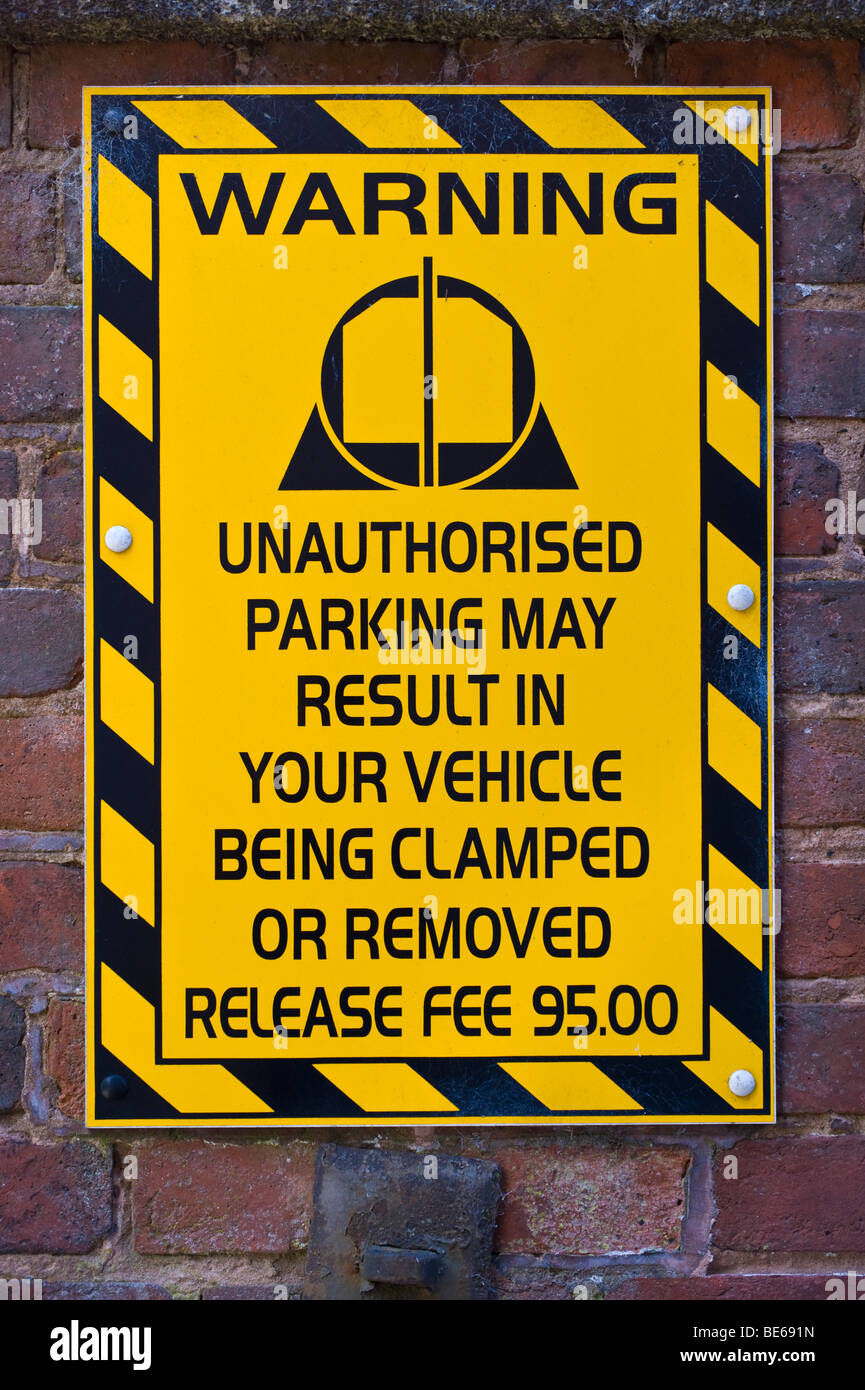 Vehicle clamping warning sign fixed to wall of car park in UK Stock