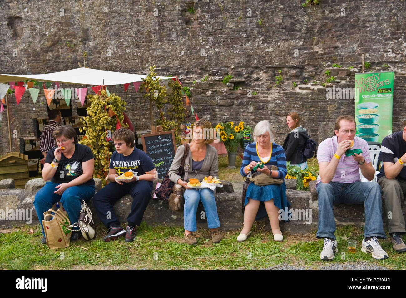 People eating snacks seated in castle grounds during Abergavenny Food