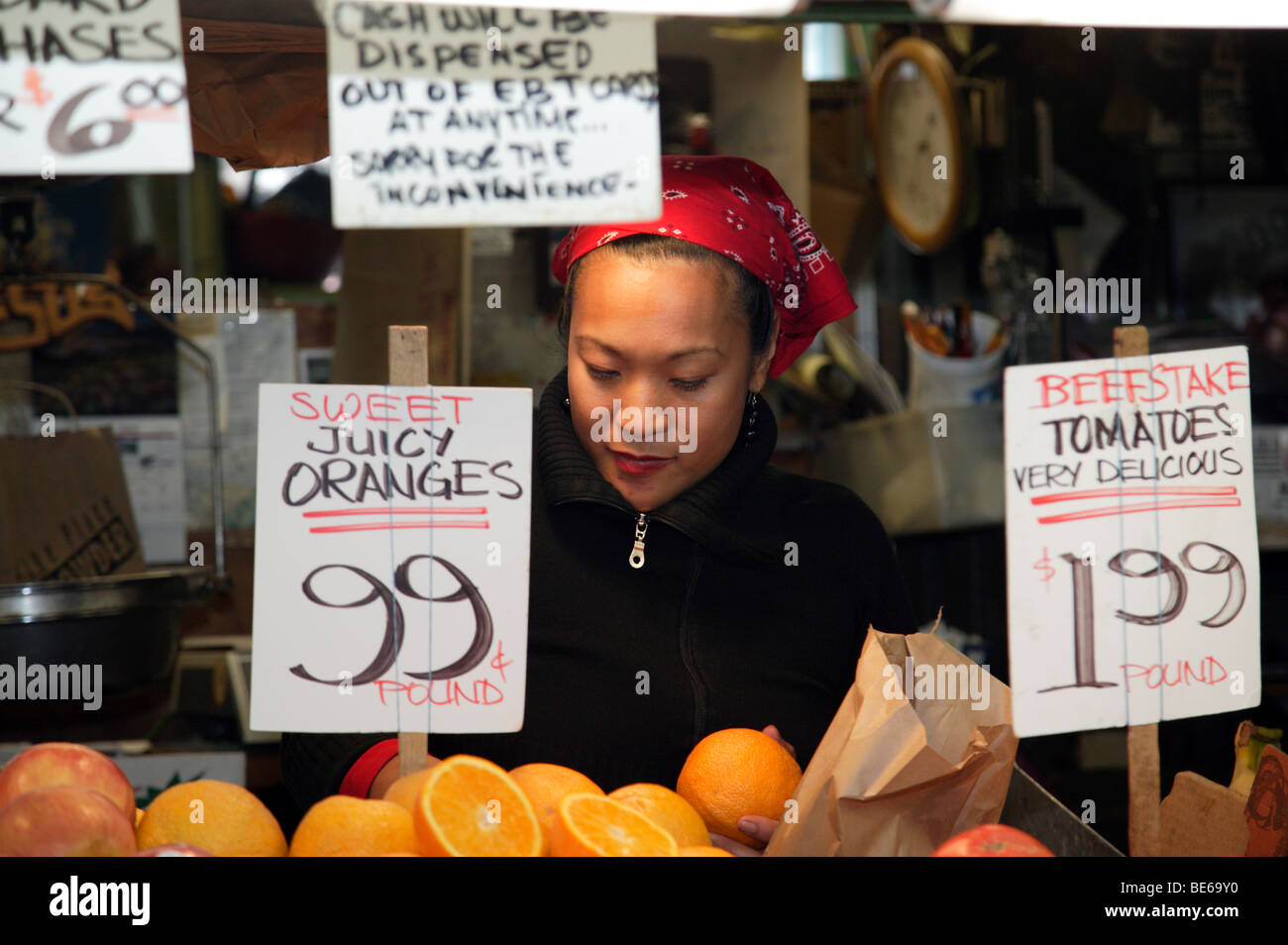 A market trader at work on a fruit and vegetable stall in the famous Pike Place Public Market, Seattle Stock Photo