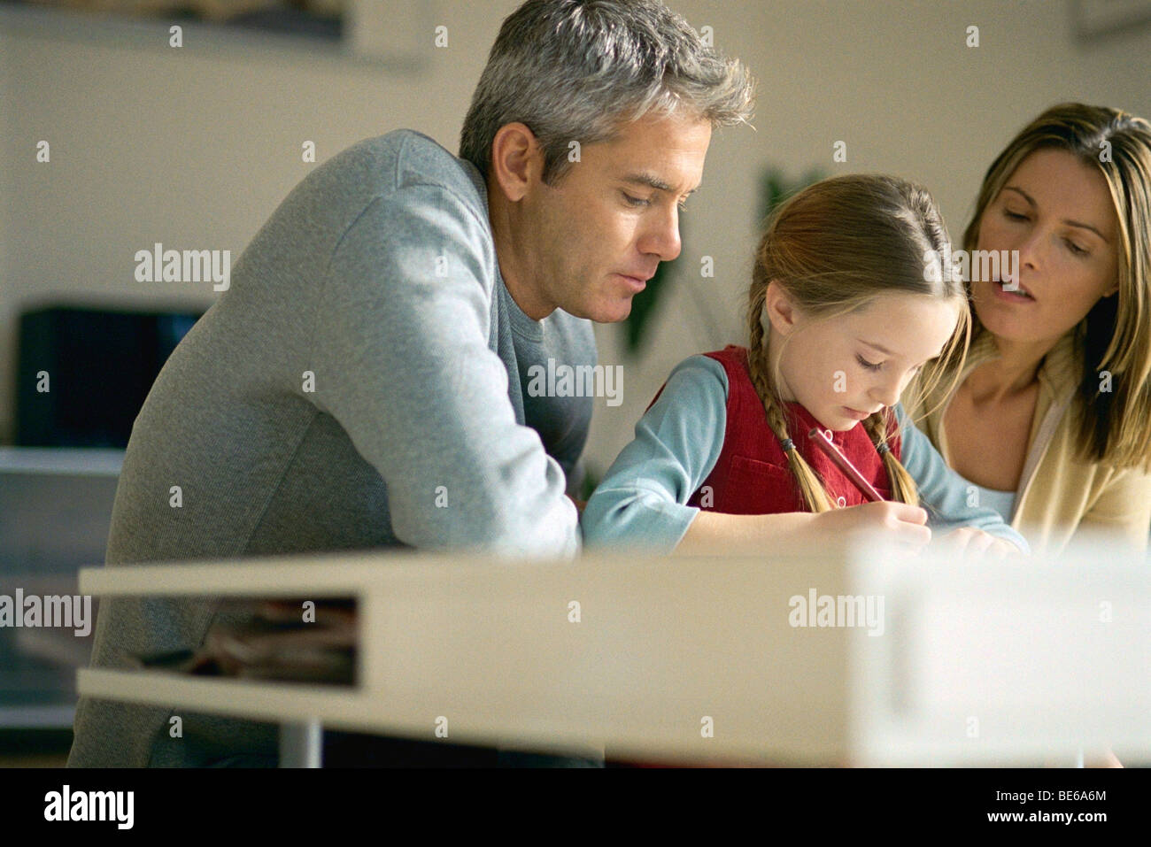 Parents helping young daughter with homework Stock Photo