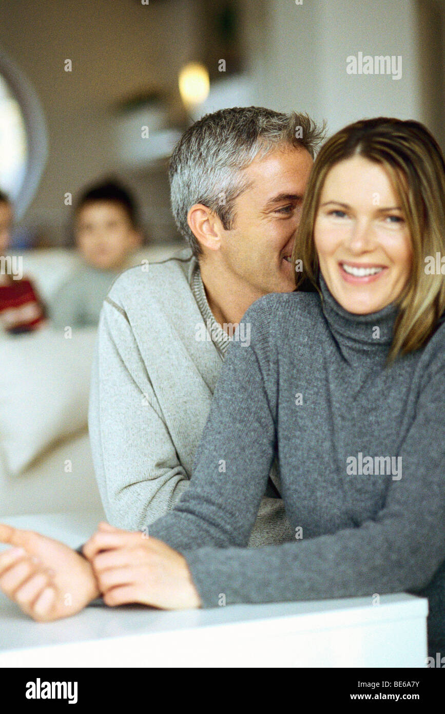 Couple sitting together, man whispering in woman's ear Stock Photo