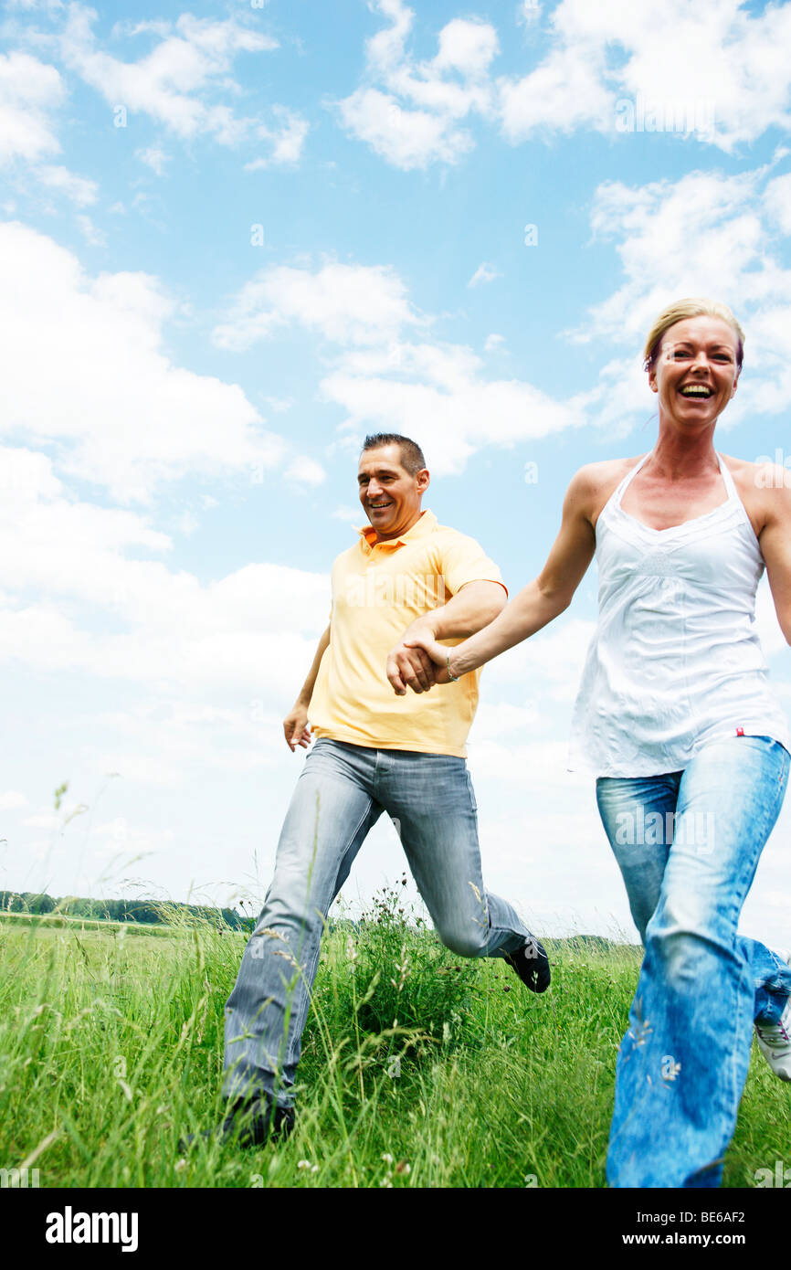 Couple running across a meadow, holding hands Stock Photo