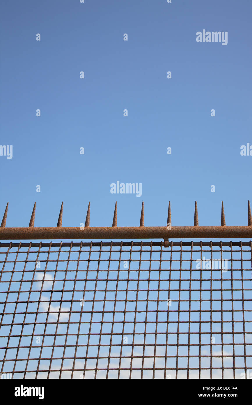 Tall, rusty iron fence with spikes against a blue sky Stock Photo Alamy