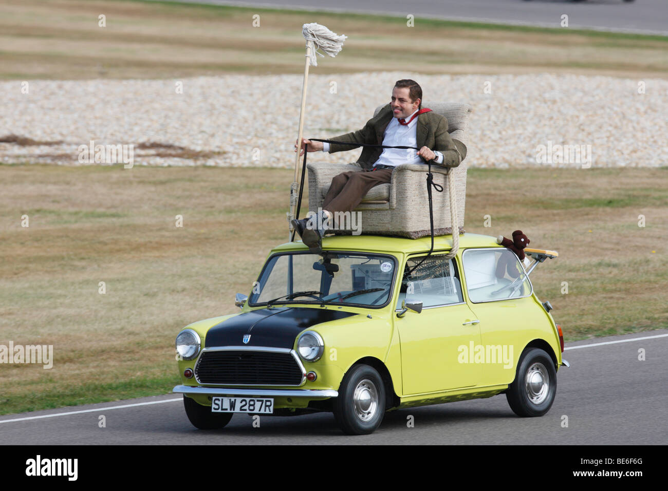 Mr Bean driving a classic Mini from arm chair on its roof Stock Photo