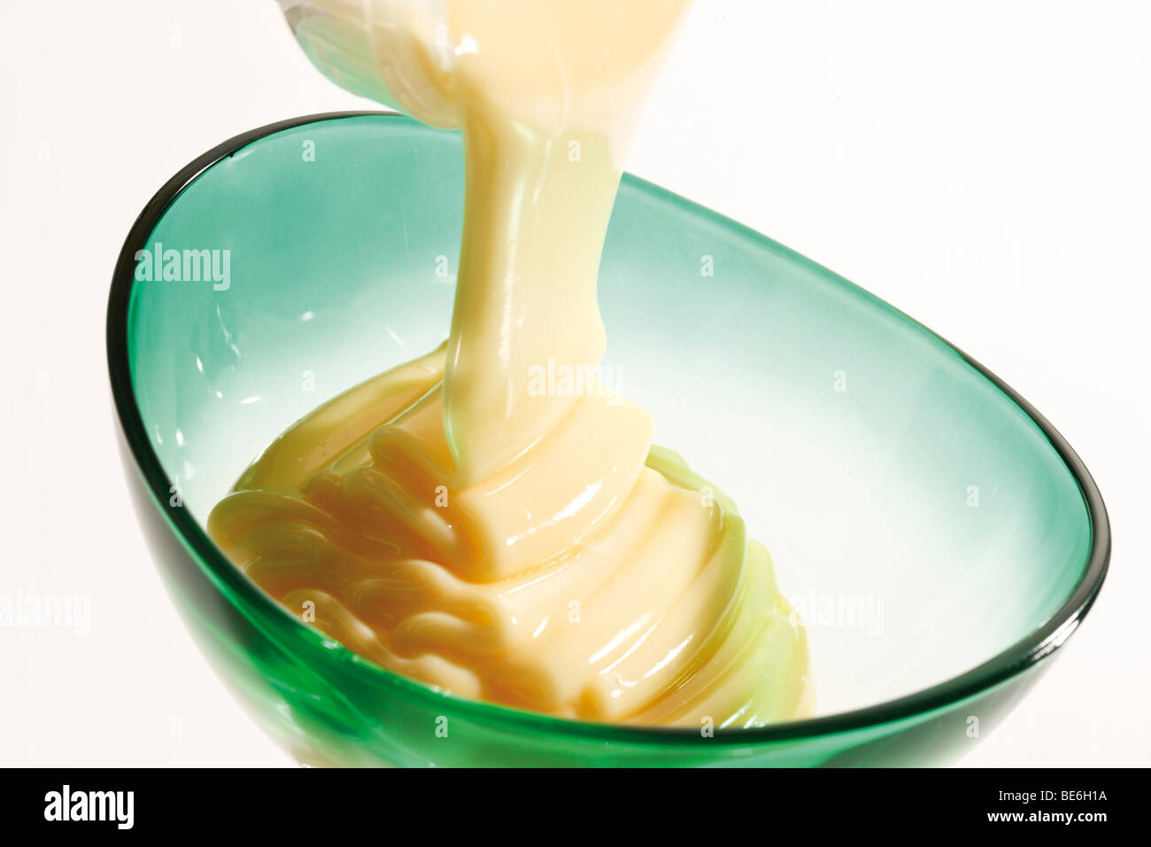 Vanilla pudding being filled into a glass bowl Stock Photo