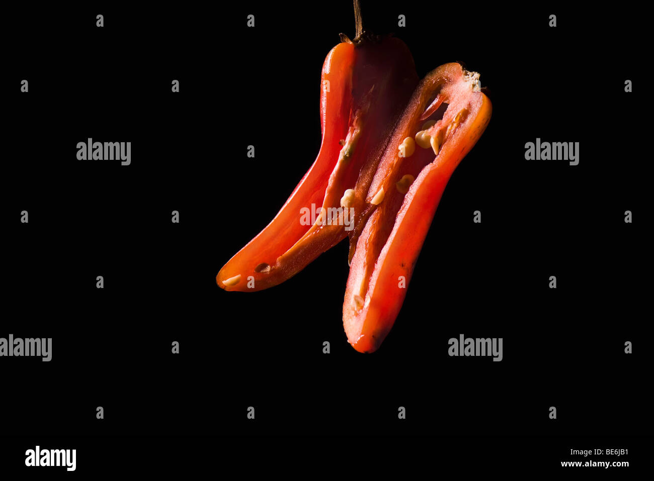 Red chili pepper sliced in half lengthwise, on black background Stock Photo