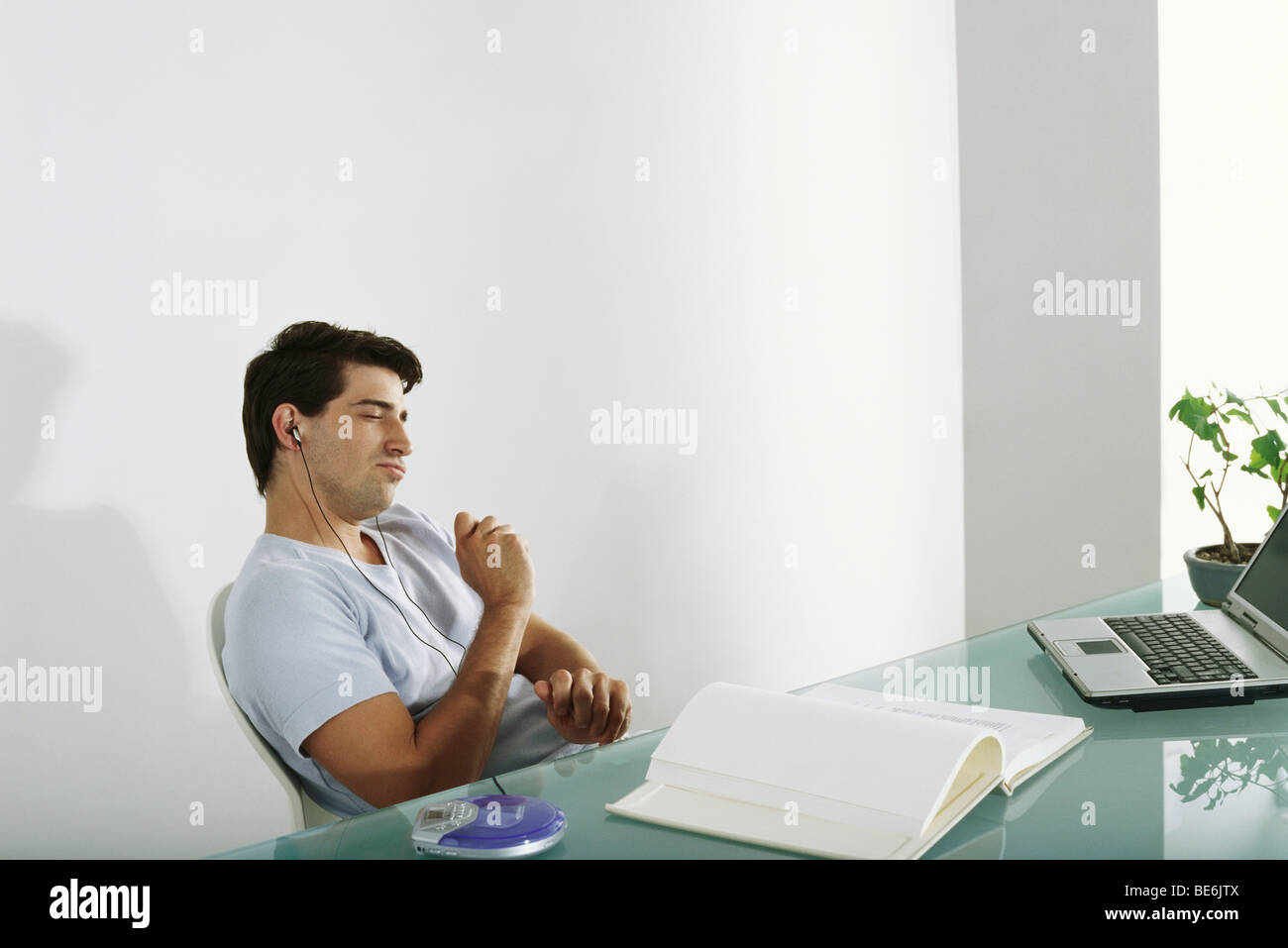 Man at desk listening to music, pretending to play drums along with song Stock Photo