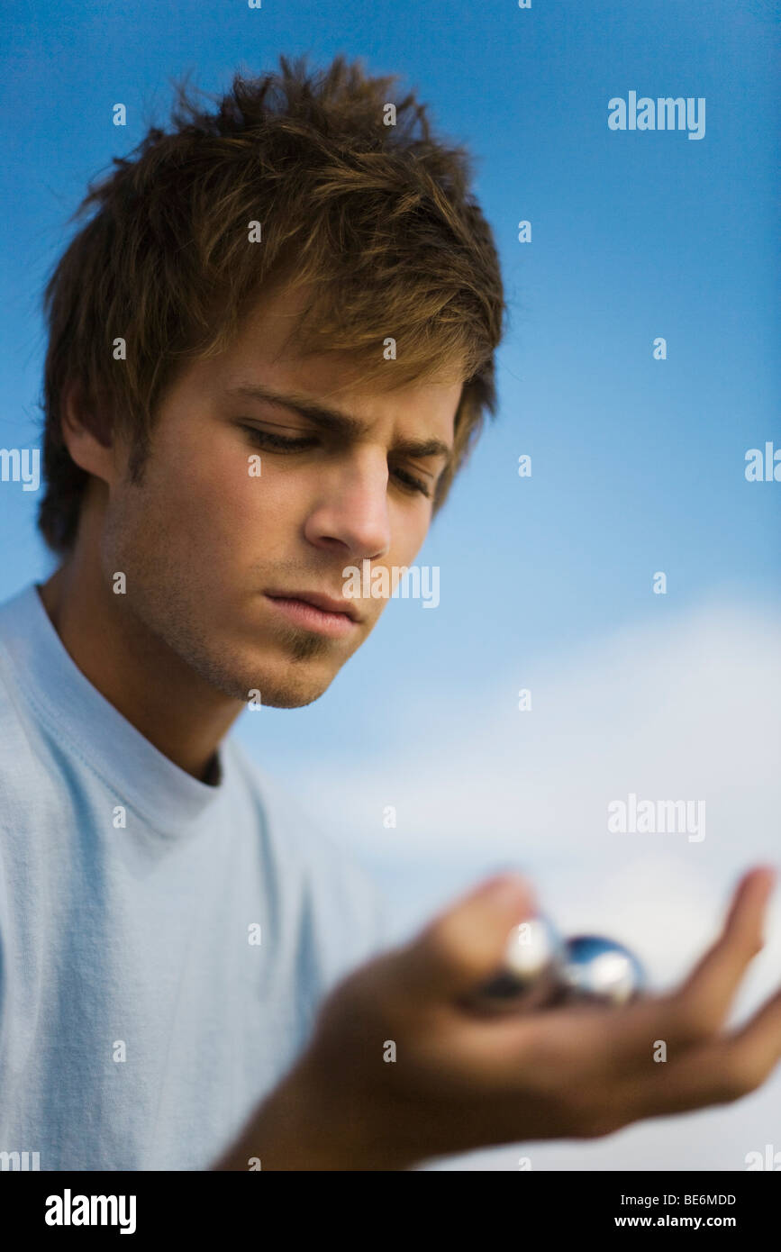 Young man looking at yin yang balls with furrowed brow Stock Photo