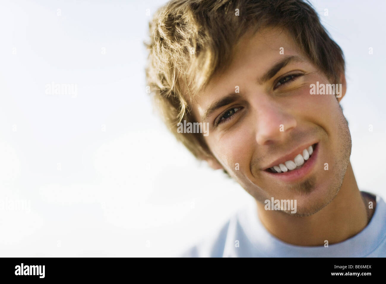 Young man smiling at camera with head tilted, portrait Stock Photo - Alamy