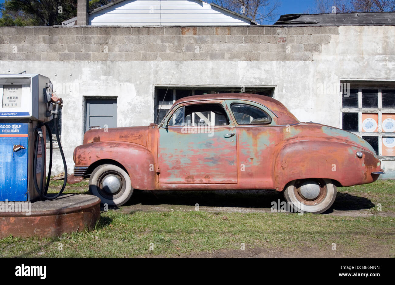 Old and rusted automobile sits outside an old gas station. Stock Photo