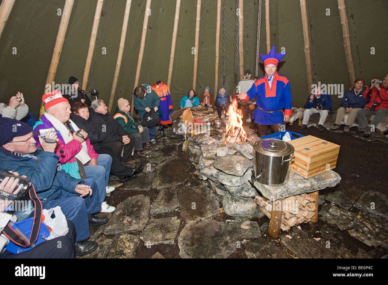 Sami man in traditional clothing talks about daily life in a large version of the the tent they use when following reindeer Stock Photo