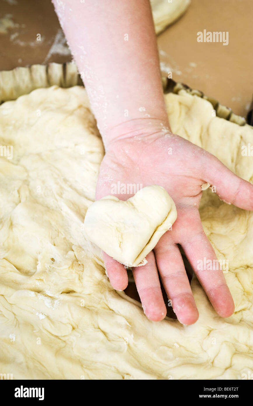 Child's hand holding heart shaped piece of dough Stock Photo