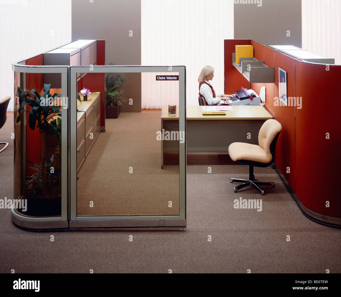 1980s office with glass wall and woman typing Stock Photo