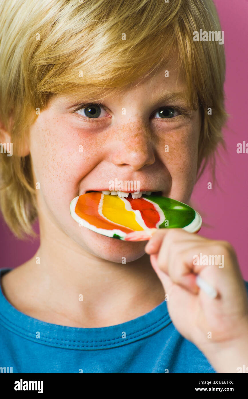 Boy biting into lollipop Stock Photo