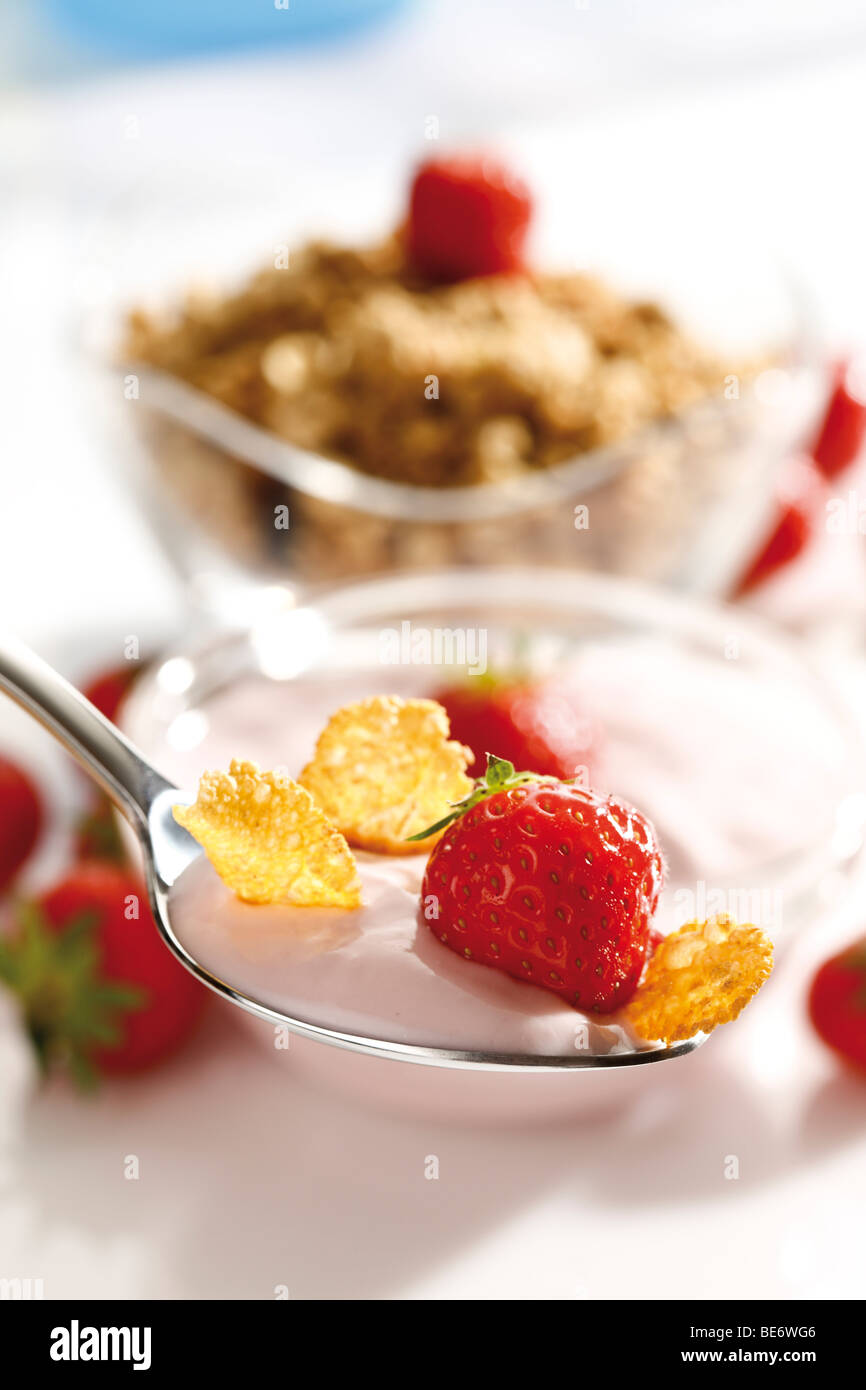 Strawberry yoghurt with cornflakes on a spoon, muesli Stock Photo