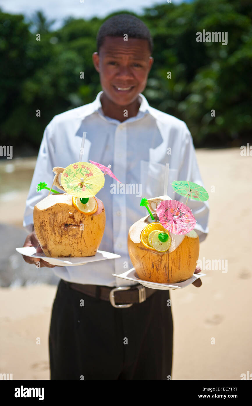 A waiter holding two decorated coconuts filled with drinks, island Mahe, Seychelles, Indian Ocean, Africa Stock Photo
