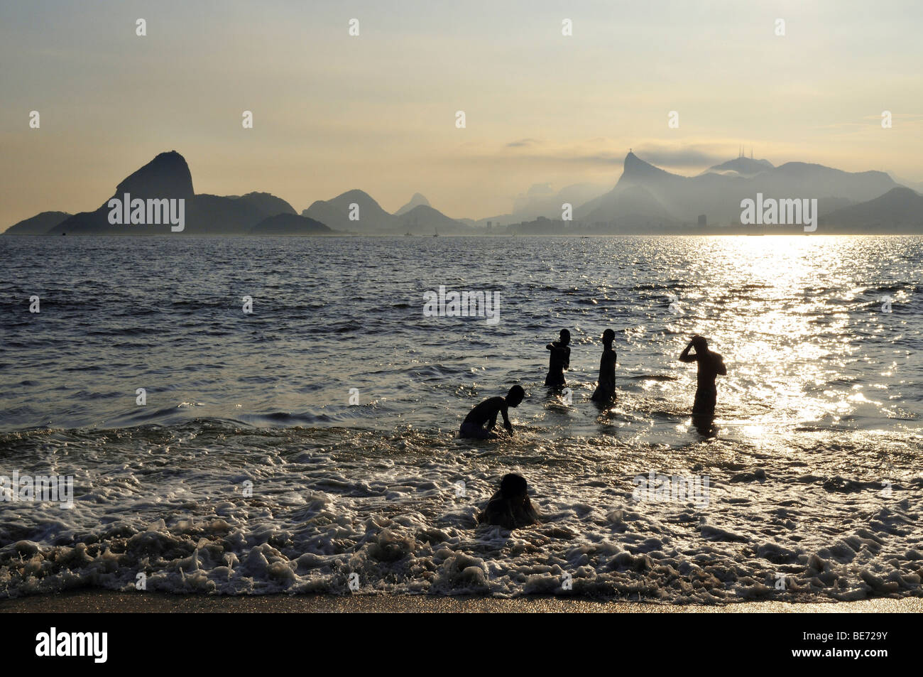 Young people in the ocean and view of the Sugarloaf Mountain and Corcovado Mountain, Niteroi, Rio de Janeiro, Brazil, South Ame Stock Photo