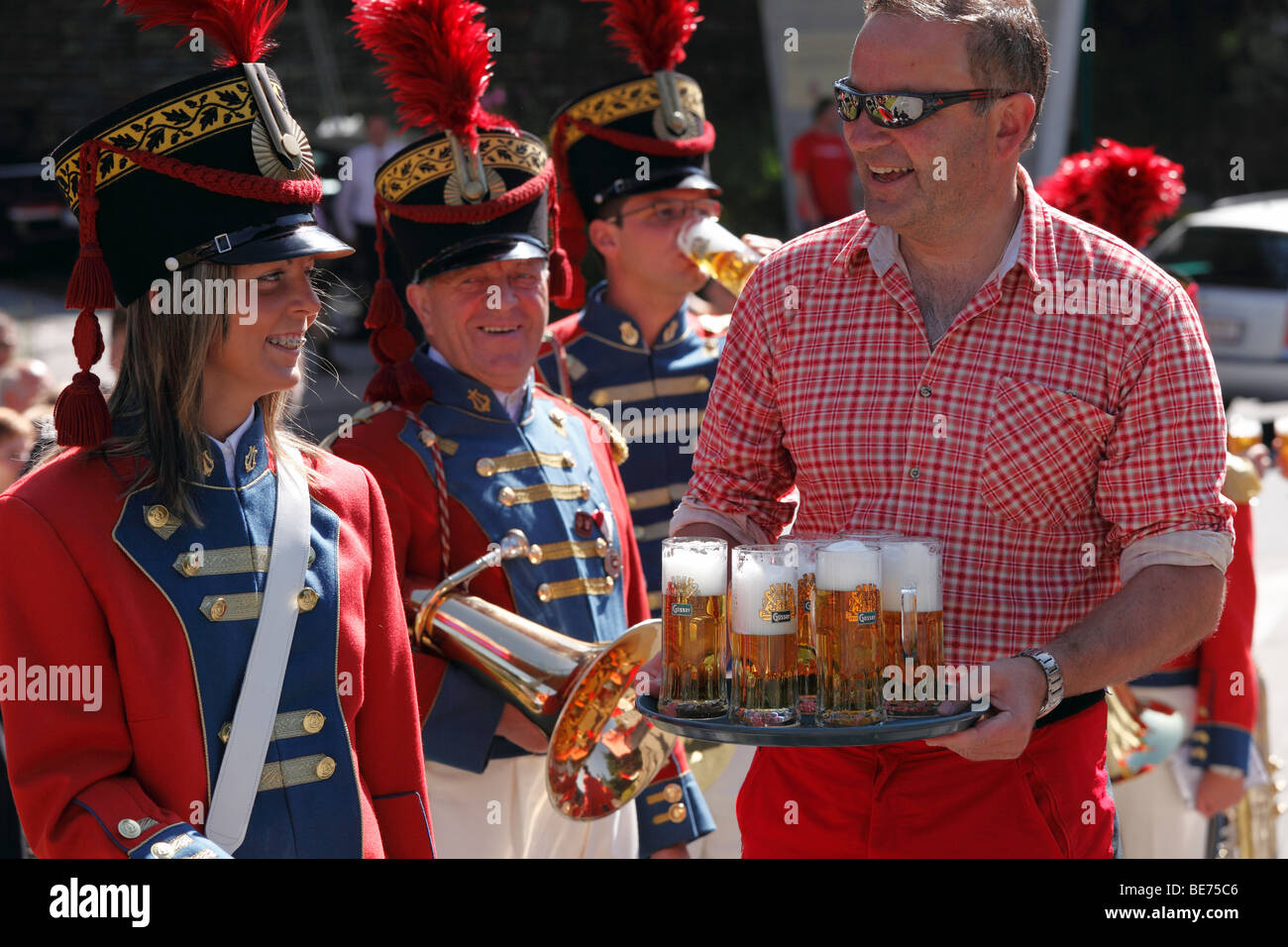 Landlord serving beer to the local music group from St Michael, at the Samson Parade, Katschberg, Lungau, Salzburg state, Salzb Stock Photo