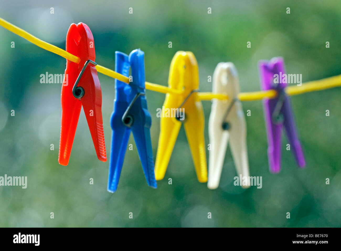 multicolored clothes pin on yellow clothes line, close up Stock Photo