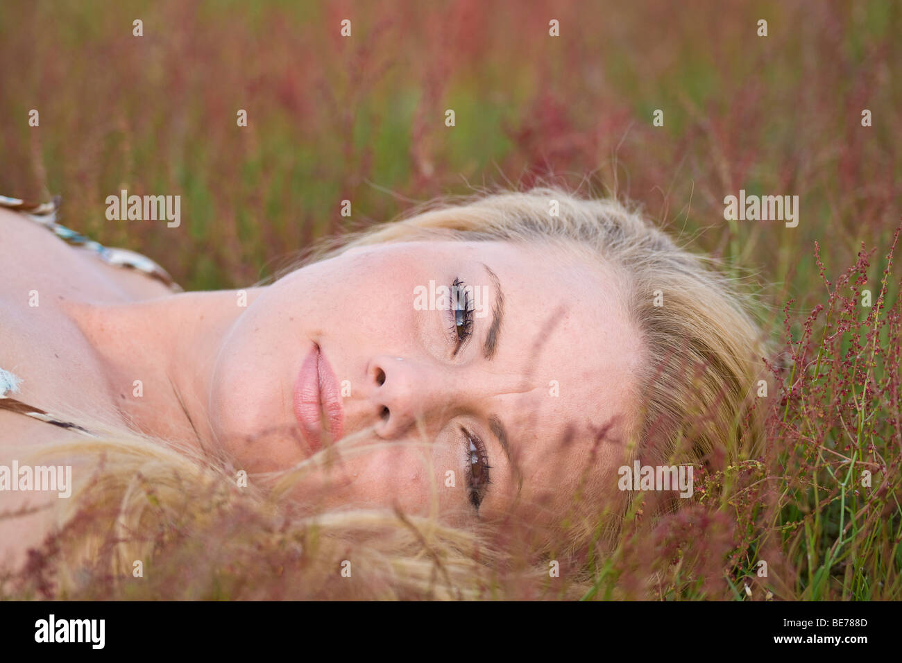 Young blonde woman lying on a meadow, relaxed Stock Photo